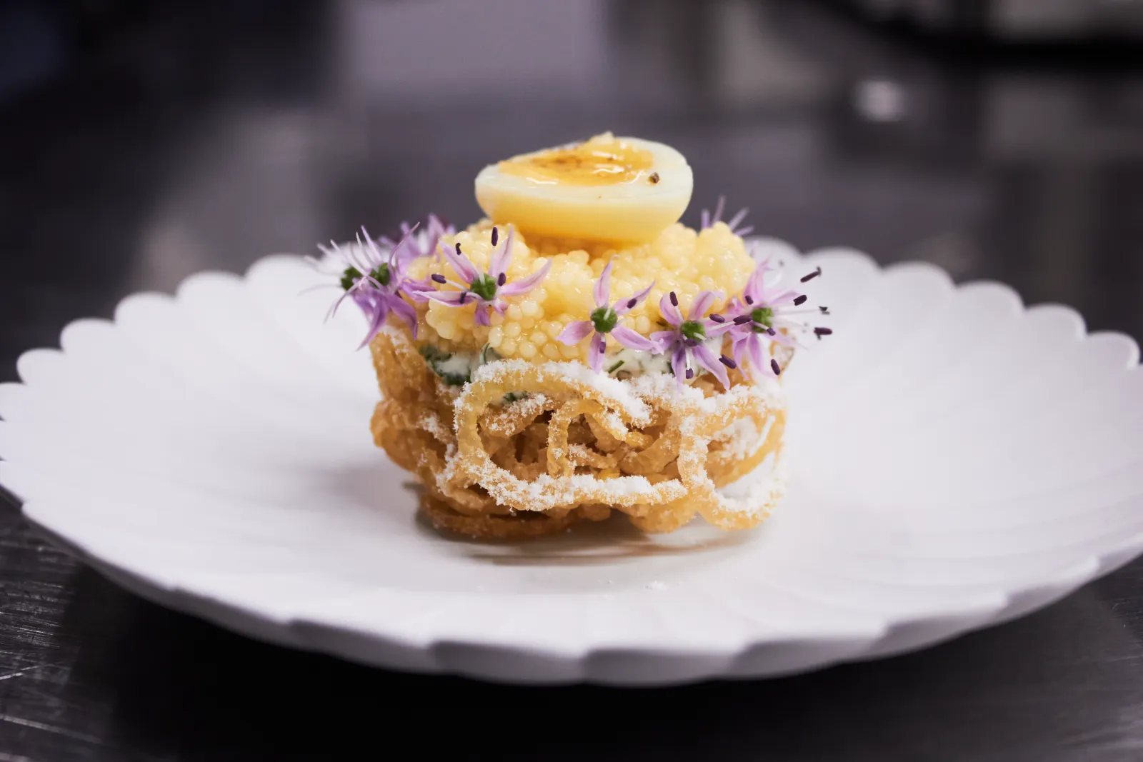 A plated course finished with Antonius Caviar, soft egg and chive blossom